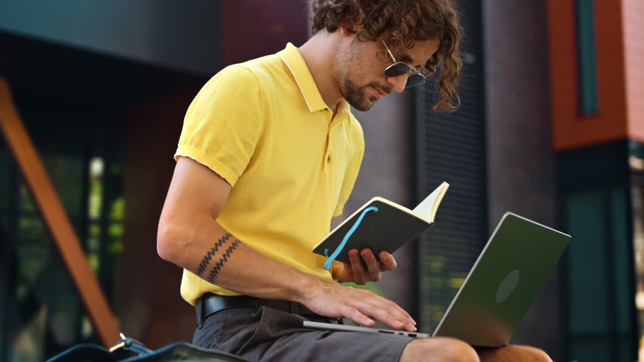 Man in yellow shirt talking standing on a bench and writing in a notebook