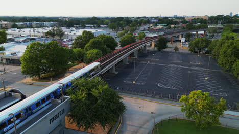 aerial view of subway train leaving station and passing on elevated line through suburbs