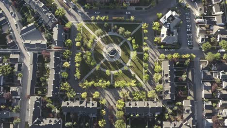 aerial birds eye view community park symetrical centered paths into a gazebo commonly used to celebrate wedding and town gatherings around low rise luxury brick homes with vintage style of sunny peace