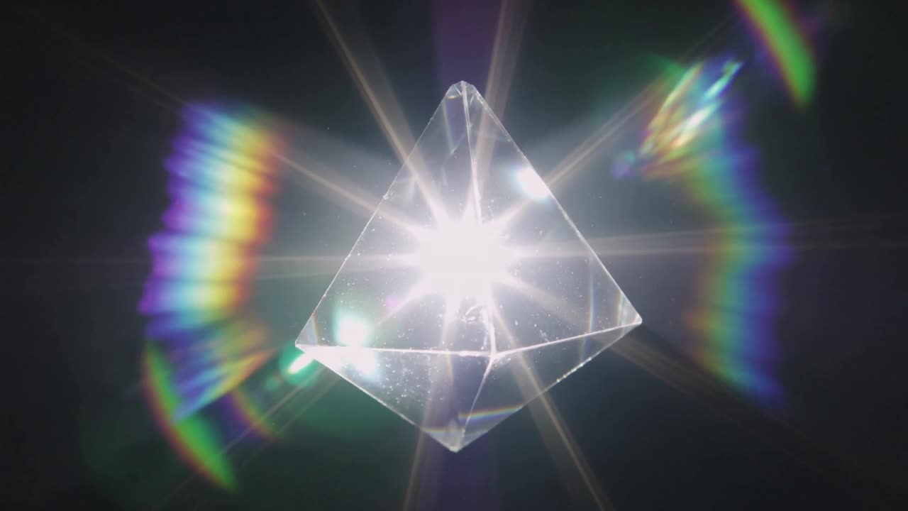 Luce puntiforme crescente, prisma centrato che produce effetti a stella e ventagli arcobaleno in studio, granelli di polvere.