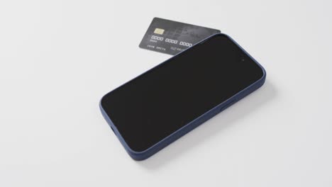 Video-of-smartphone-with-blank-screen,-boxes-and-credit-card-with-copy-space-on-white-background