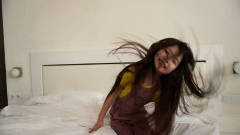 Lovely-asian-looking-listening-using-headphones-on-the-bed-and-funny-dancing