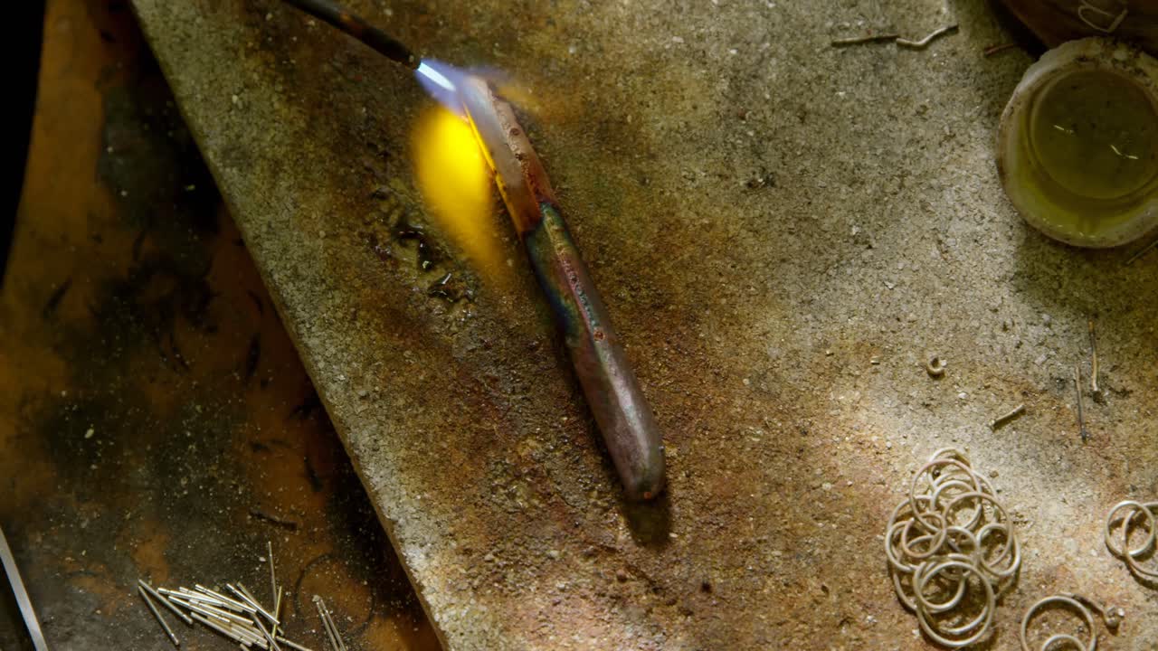 Jewelry designer welding piece of metal in workshop 4k