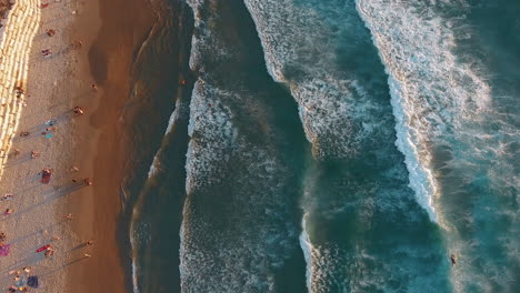 aerial top down view of a beach with a population, flying forward