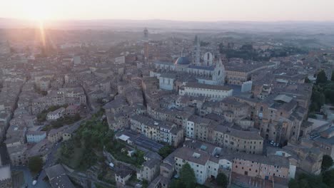 aerial view of siena, tuscany, italy at sunrise with duomo di siena, torre del mangia, sun flare, and medieval town in 4k