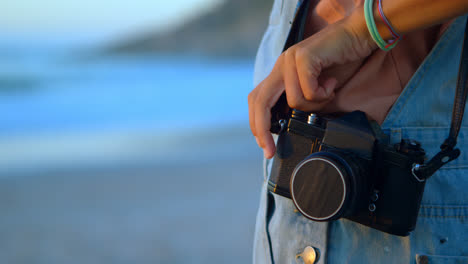 woman standing with vintage camera inn the beach 4k