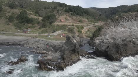 Aerial-circling-push-oçut-shot-of-people-and-seagulls-in-a-rock-formation-in-the-coastline-of-"Pilolcura"-Chile,-high-frame-rate