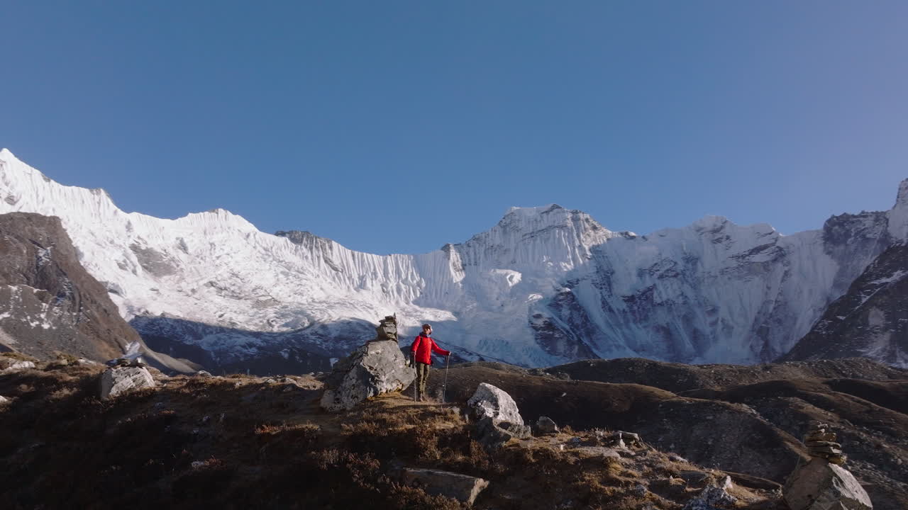 Un turista sul percorso di trekking del Campo Base dell'Everest in Nepal si guarda intorno il paesaggio himalayano durante la luce serale. Ripresa aerea con drone con l'Ama Dablam che si staglia sullo sfondo