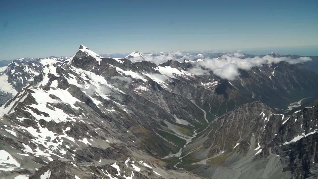 cámara lenta: toma aérea desde un vuelo panorámico sobre la costa oeste del glaciar franz josef, aoraki mount cook, parque nacional con nubes, montañas rocosas nevadas y océano en el fondo