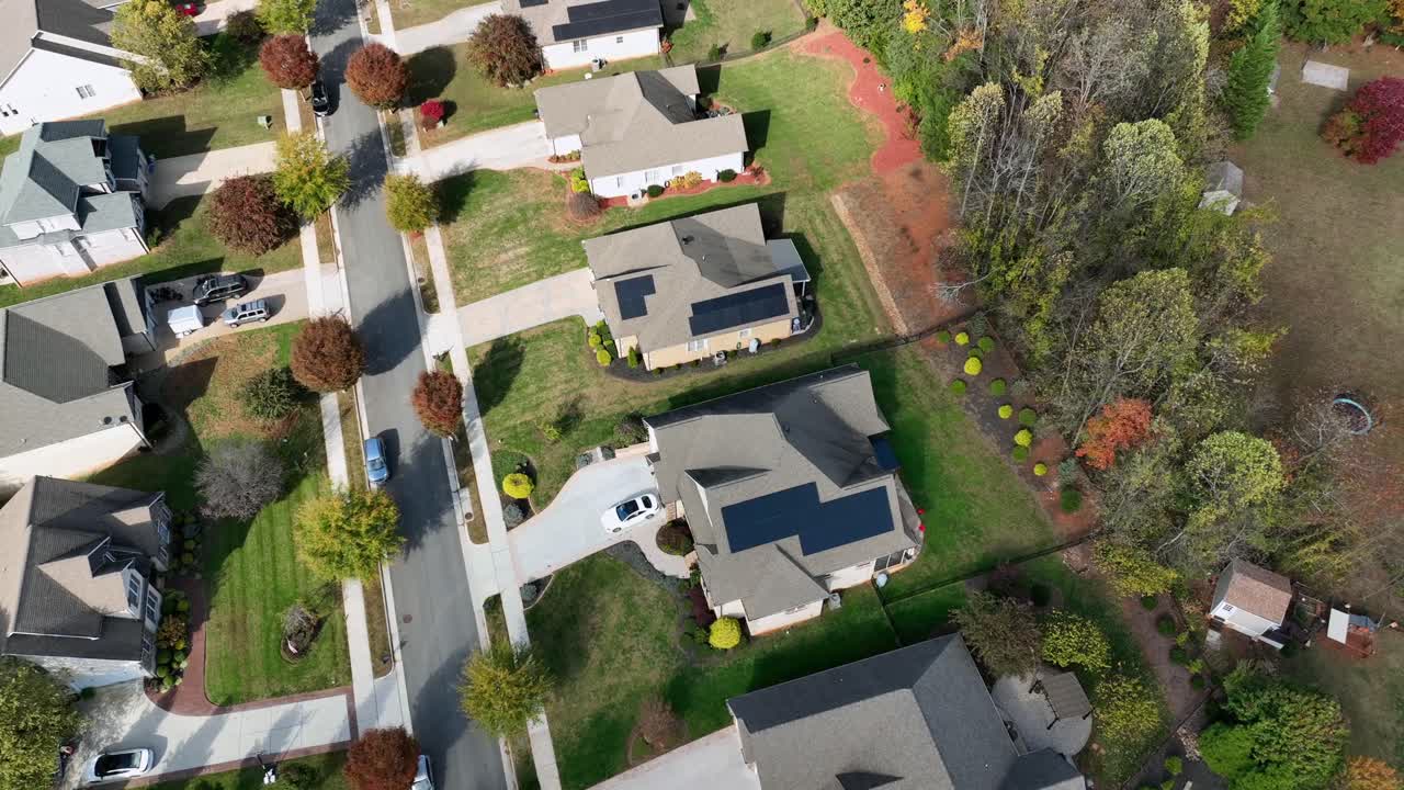 Residential America suburb with modern homes, clean streets, autumn colors, solar panels on roof and well-kept yards in quiet upscale neighborhood. drone tilt up wide shot. Sunny day in fall