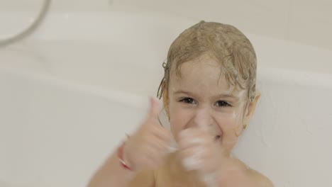 attractive three years old girl takes a bath. cleaning and washing hair