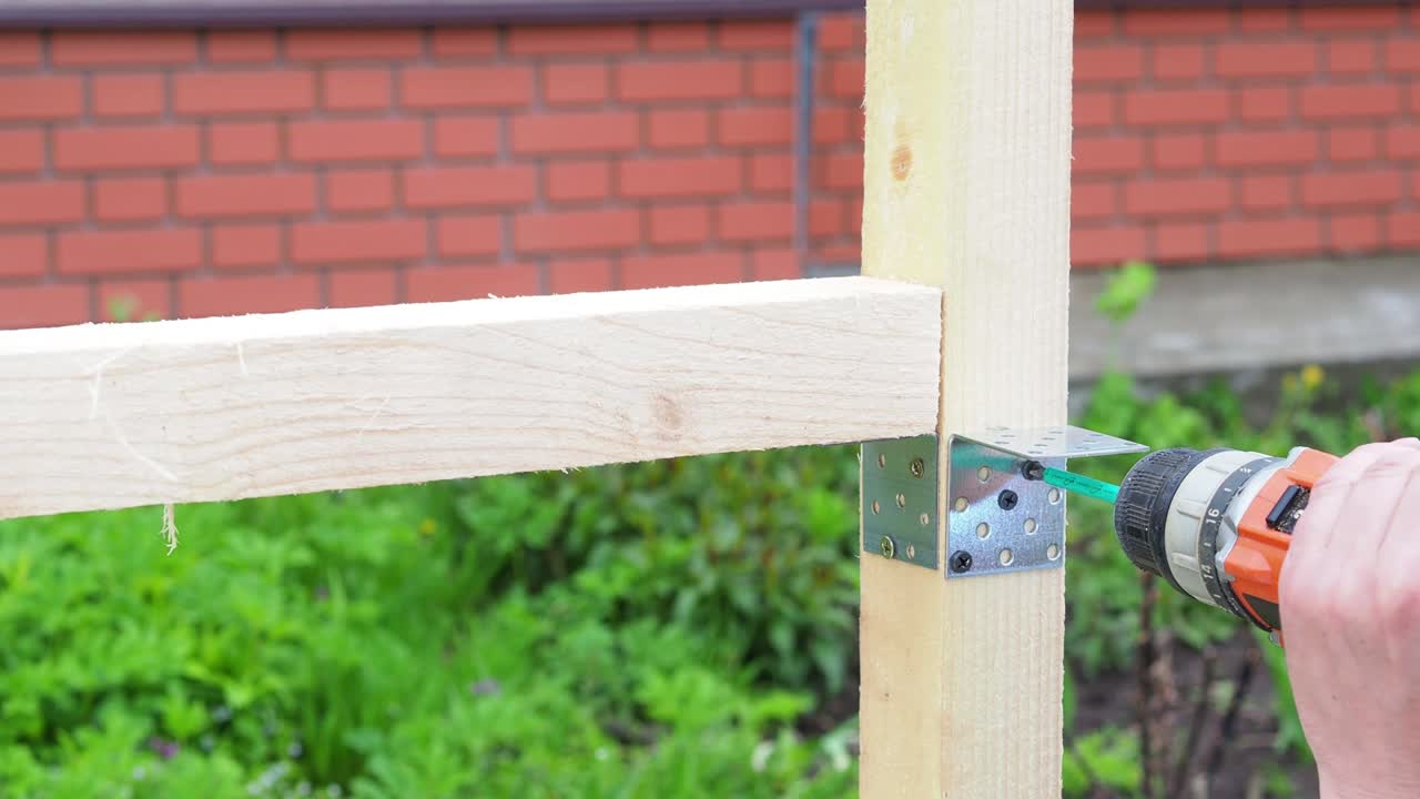The worker screws the metal corner to the board with a screwdriver. Construction. close-up.