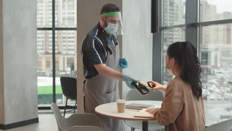 woman paying with cellphone in restaurant