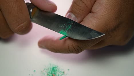 Footage-of-hands-slowly-sharpening-a-pencil-and-some-coloured-pencils-with-a-sharp-knife