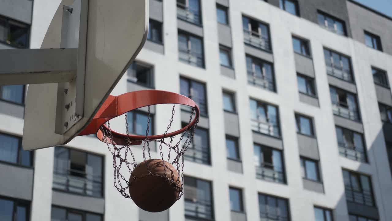 el baloncesto naranja golpea la canasta, la cancha de baloncesto en la calle, día soleado