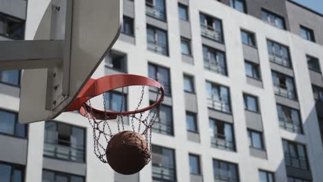 orange basketball hits basket, basketball court on street,sunny day