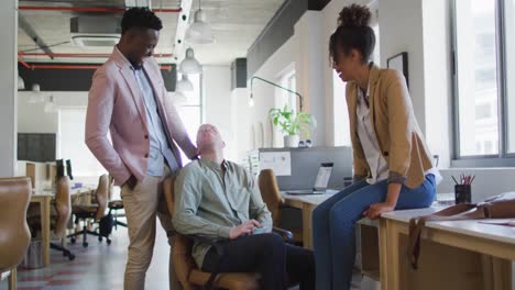 portrait of happy diverse business people discussing at table in creative office