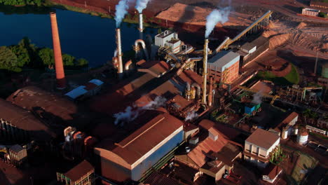 drone aerial landscape of ethanol production plant warehouse facility factory buildings with steam turbines in countryside rural town by lake and crops brazil south america industry refinery