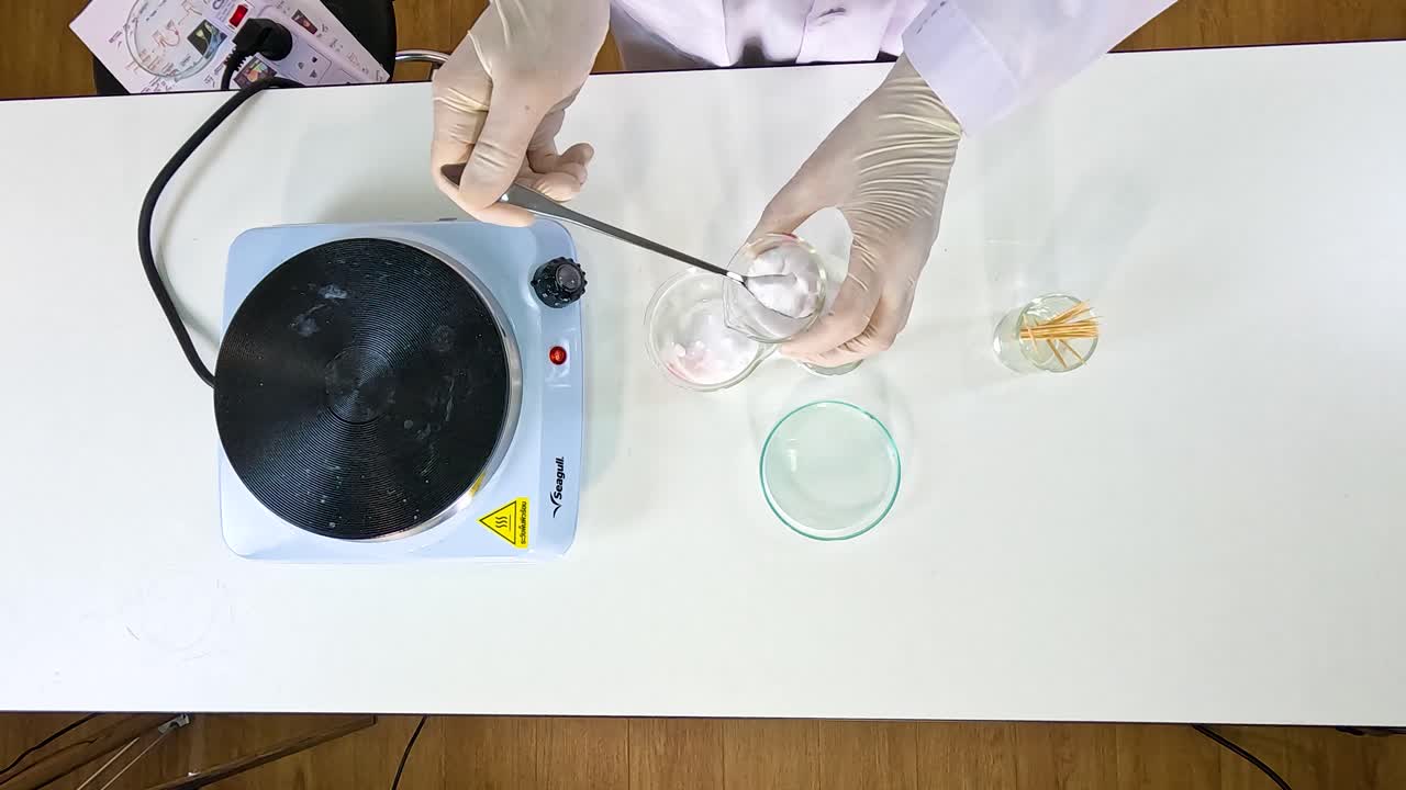 A scientist conducts a sodium acetate crystallization experiment using a hot plate and glassware in a well-lit laboratory