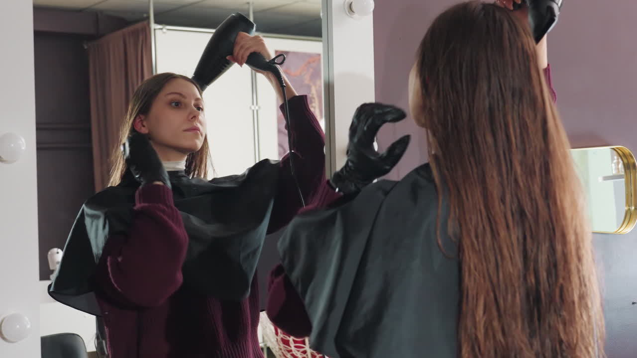 mirror view captures hairstyling process, stylist finishing touches as client observes in mirror, client observes hairstyle adjustments made by stylist during final blowdry session