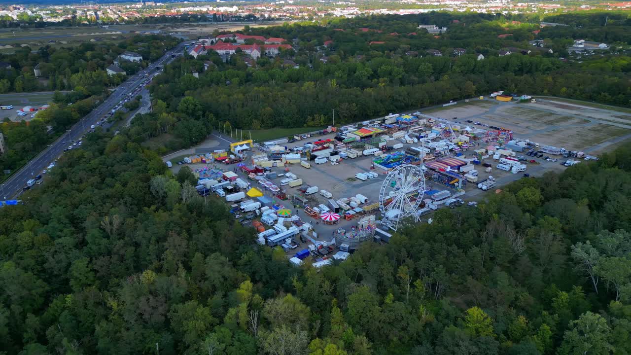 Berlin funfair showing a Ferris wheel, amusement rides, and various stalls from an aerial perspective. Unique aerial view flight panorama orbit drone