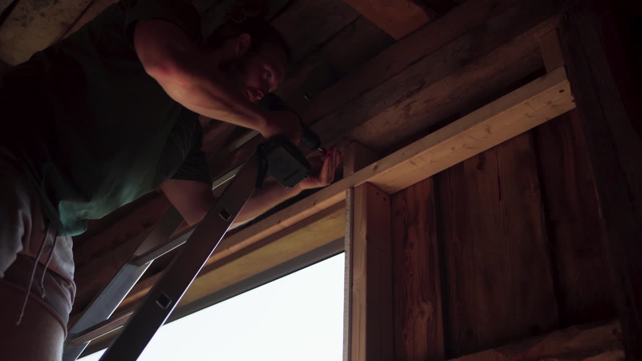 Uomo che assembla il telaio in legno di una finestra usando un avvitatore elettrico