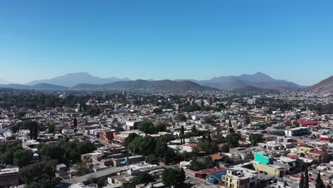 Soar-over-Saltillo,-Mexico-in-a-stunning-circular-aerial-shot-revealing-the-city's-skyline-against-majestic-mountains-and-a-clear-blue-sky