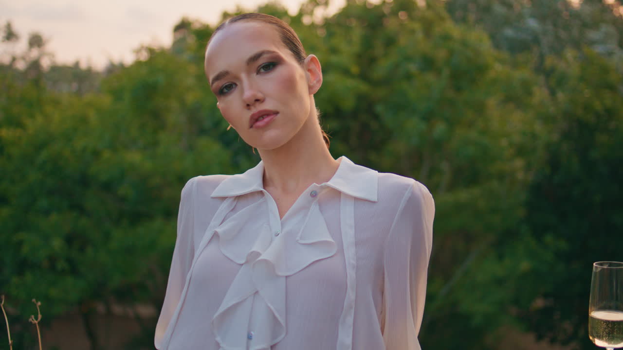 уверенная женщина стоит на деревьях, зелень смотрит вблизи на камеру. модель позирует.