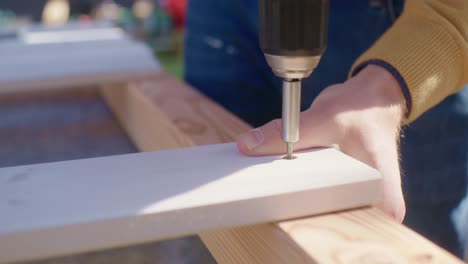 close up of screwing in a screw to a wood plank