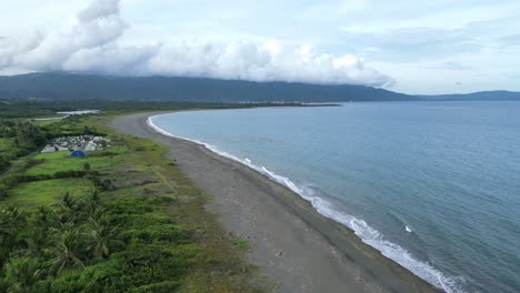 Luftaufnahme,-Drohnenaufnahme-Eines-Leeren,-Breiten-Strandes-Mit-Wolken-Und-Bergen-Im-Hintergrund-In-Der-Abenddämmerung