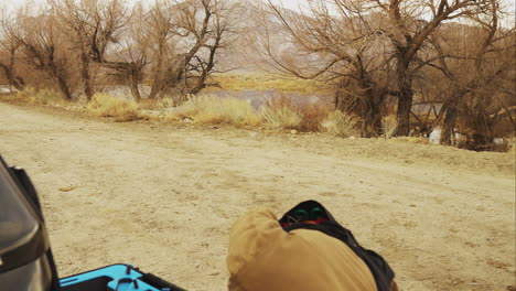 medium shot of a man in the high desert with thick black glasses and a mustache opening the case and putting away a white drone in the bed of a pickup truck