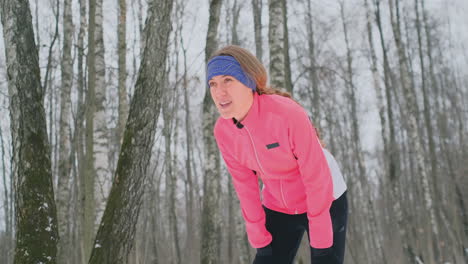 A-young-woman-on-a-morning-jog-in-the-winter-forest-was-tired-and-stopped-to-catch-his-breath.-He-recovered-his-strength-and-overcame-fatigue-and-continued-to-run.-Perseverance-and-overcoming-weakness.-Push-forward