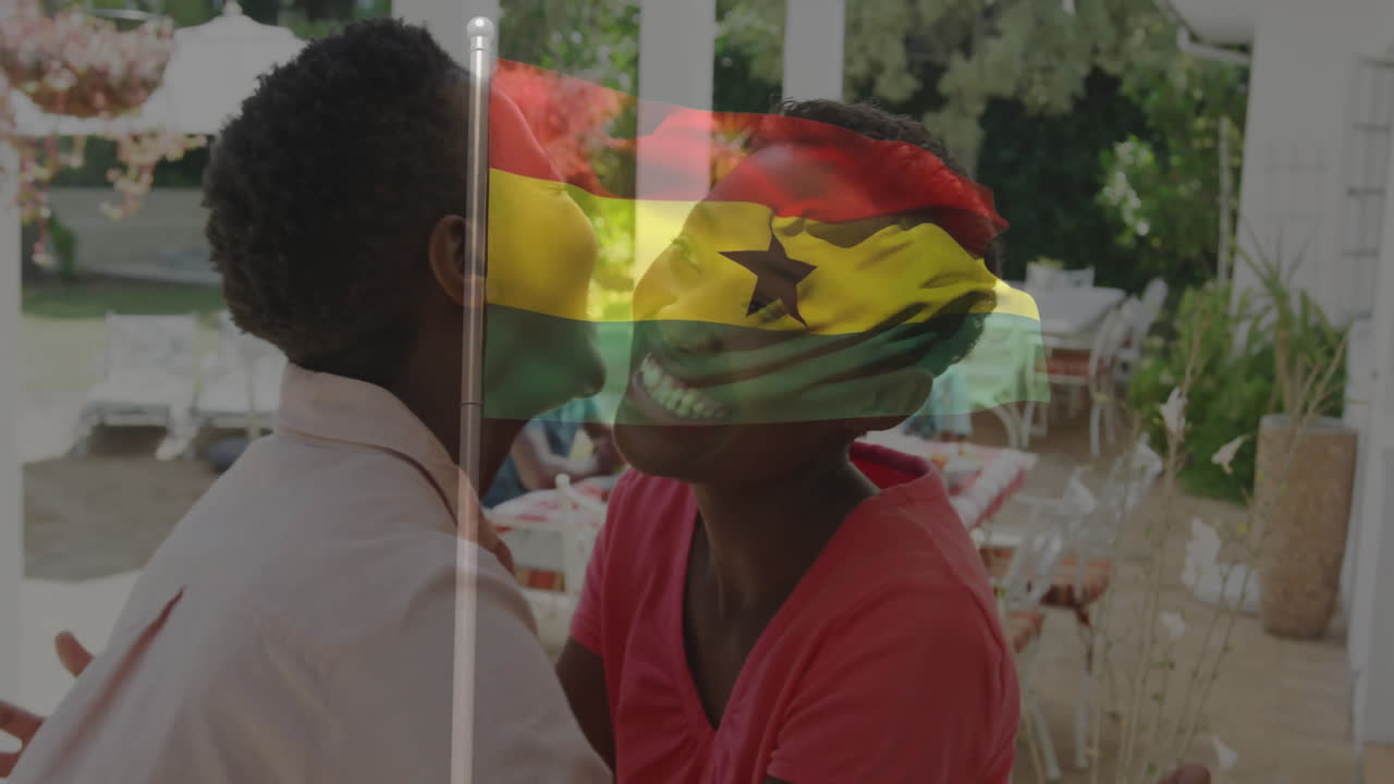 Embracing with Ghana flag overlay, two people standing near outdoor dining area