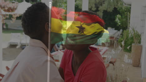 embracing with ghana flag overlay, two people standing near outdoor dining area