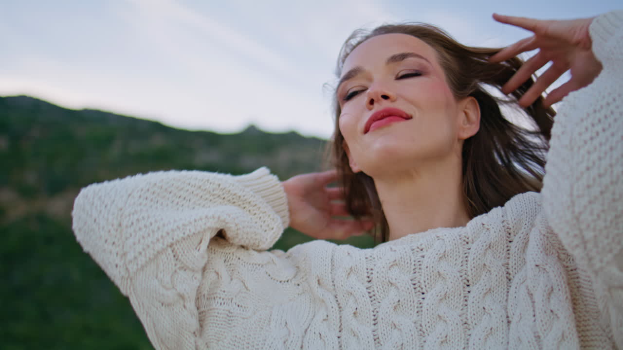 Brunette enjoy windy morning standing near green hills closeup. Portrait woman