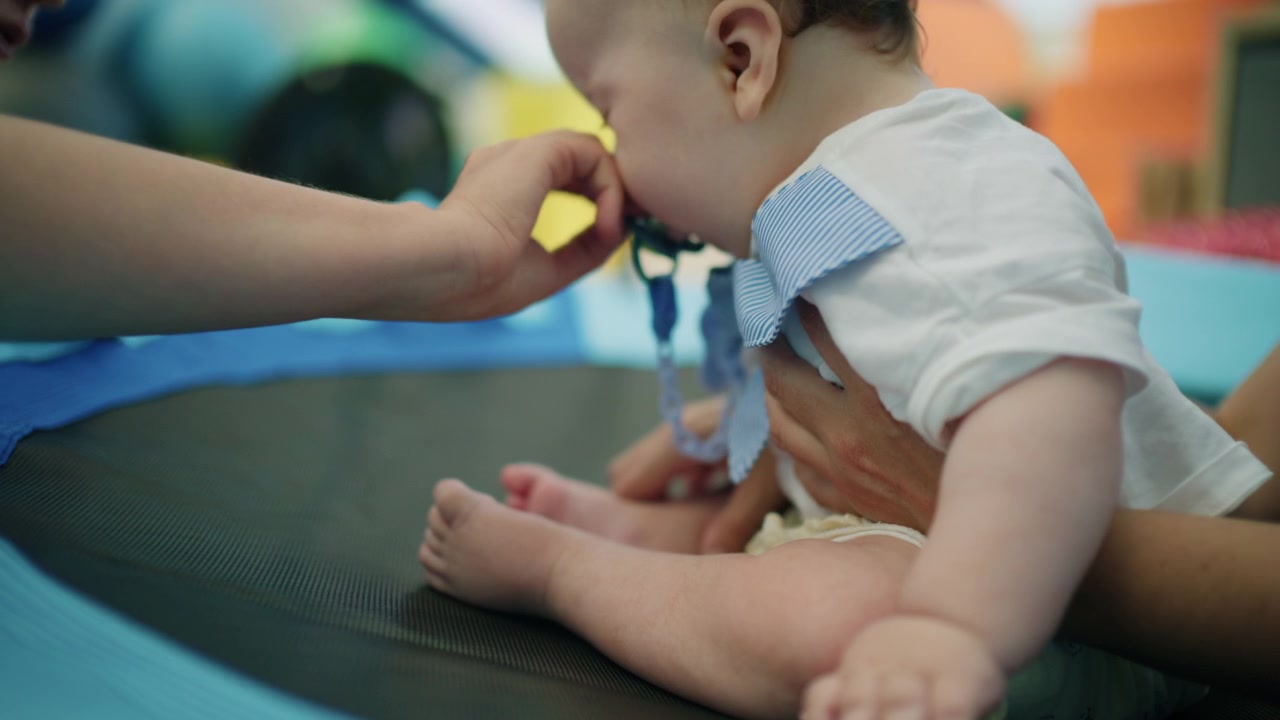Baby performing exercises with assistance on a mat. Focus on pediatric therapy fostering strength and motor skills development
