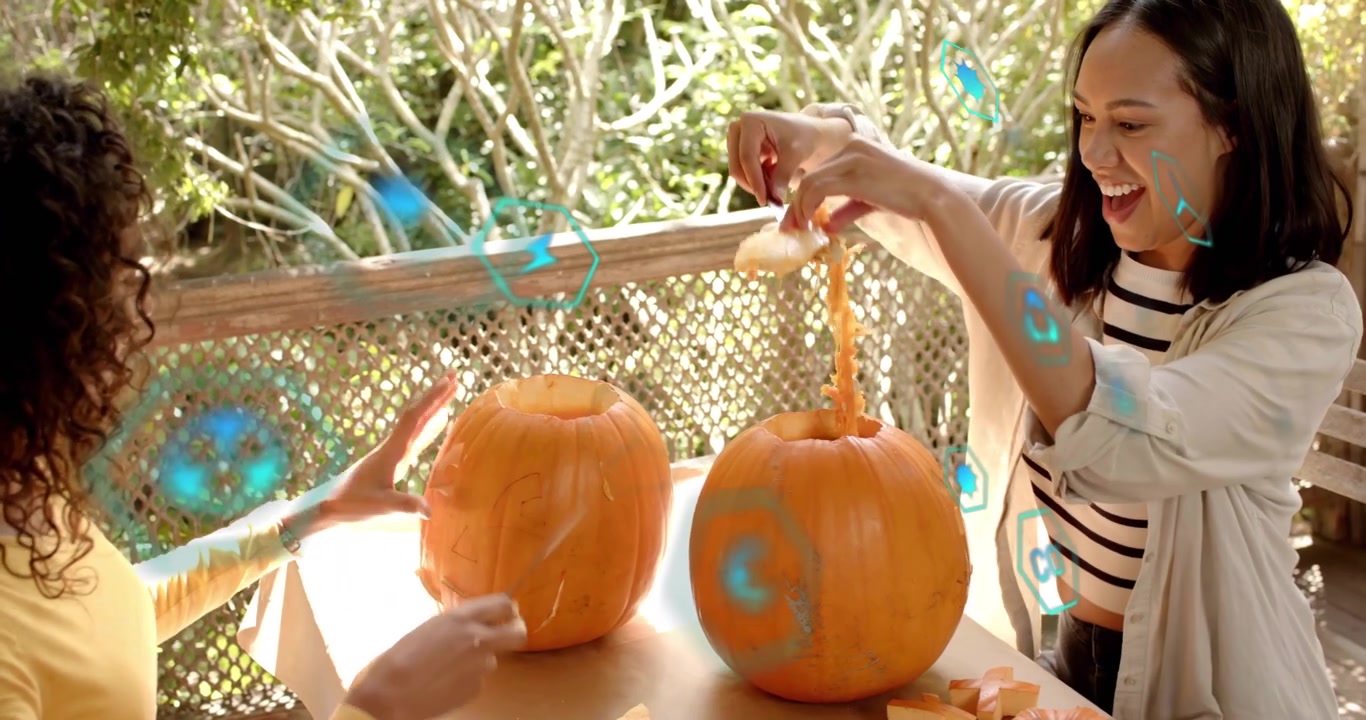 Two women positioning pumpkins on porch table and carving lids open, extracting pulp for DIY design