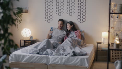 couple in bed using smartphone