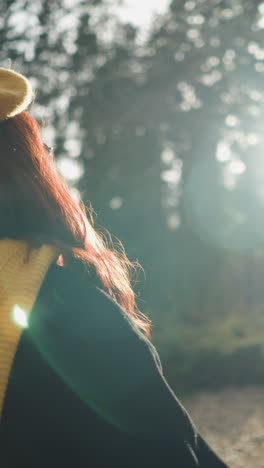 lady in beret and muffler walks along forest path, shielding sun rays with her hand, sunlight creates warm glow around her as she enjoys peaceful autumn scenery surrounded by trees and golden foliage