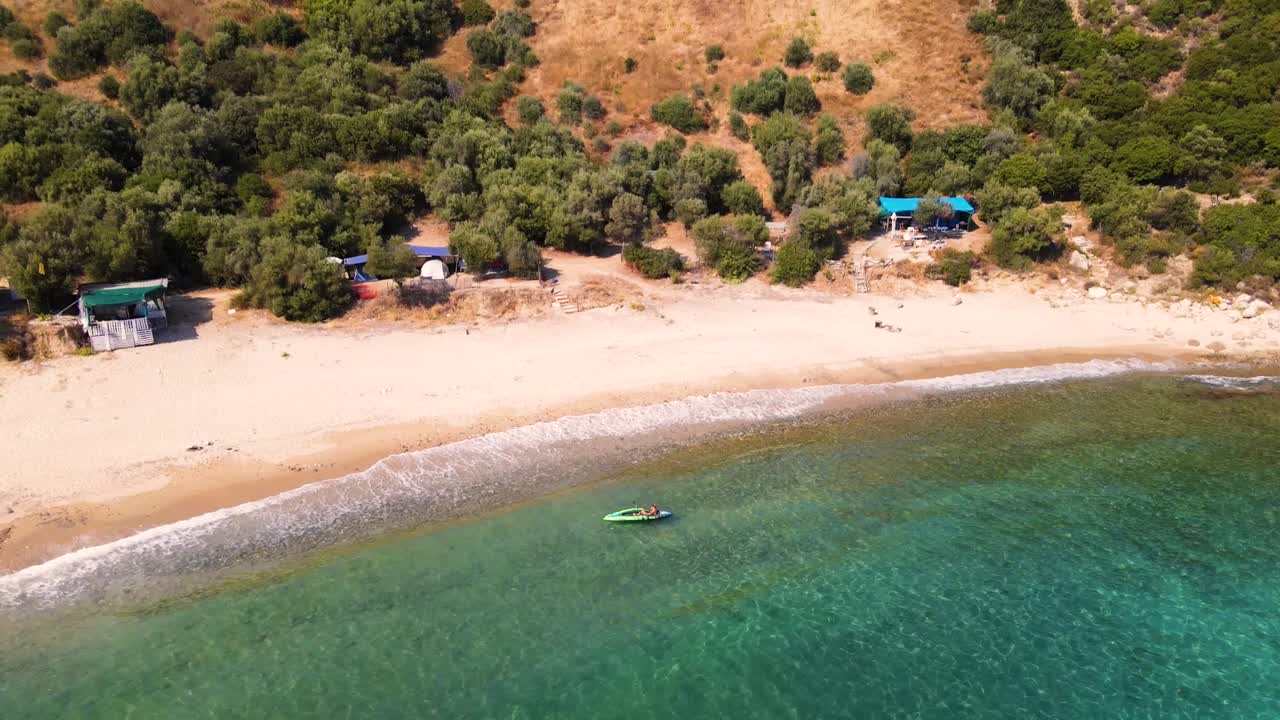Aerial drone clip over a beautiful beach in Kavala, Macedonia, Greece with a man in a canoe at the shore