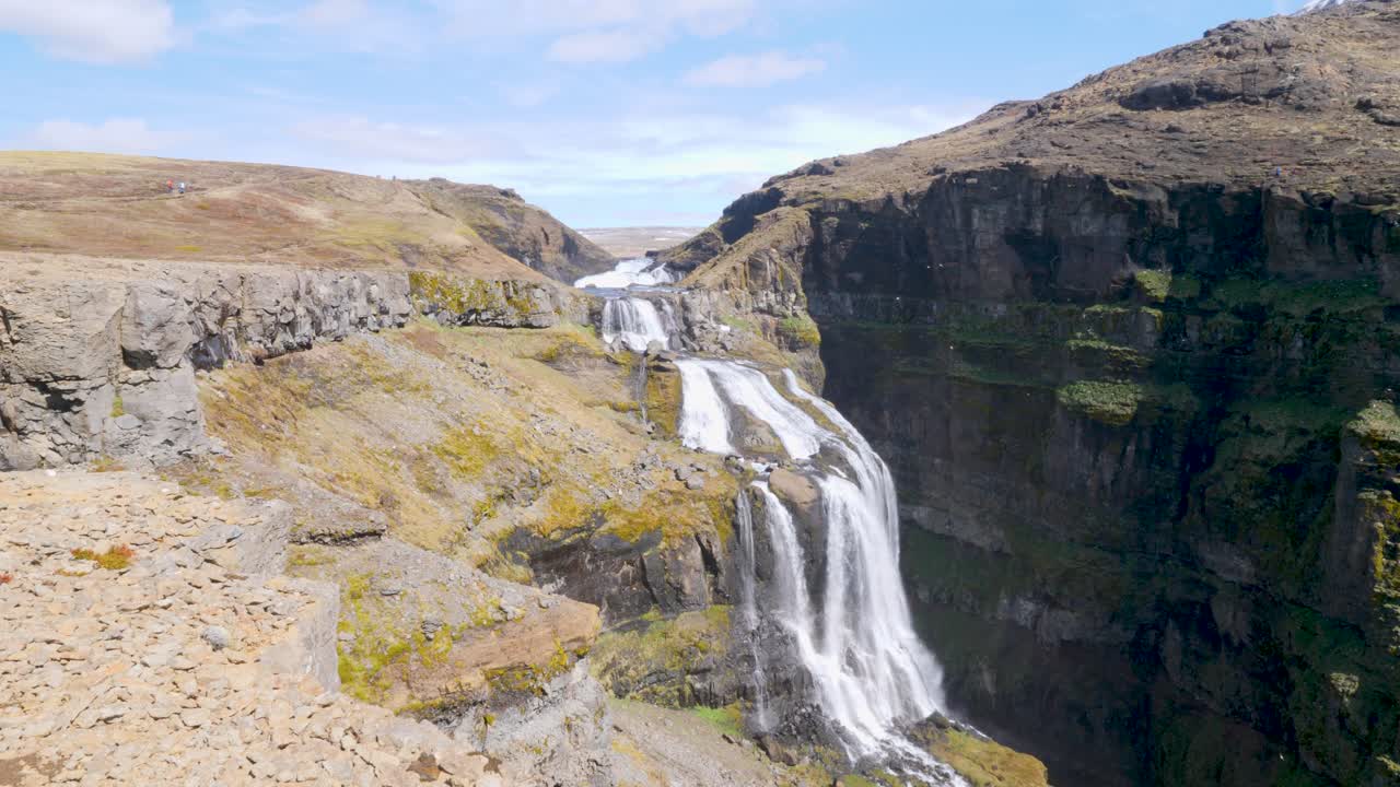 una fuerte corriente de agua cayendo sobre la cascada de glymur en islandia en un día soleado
