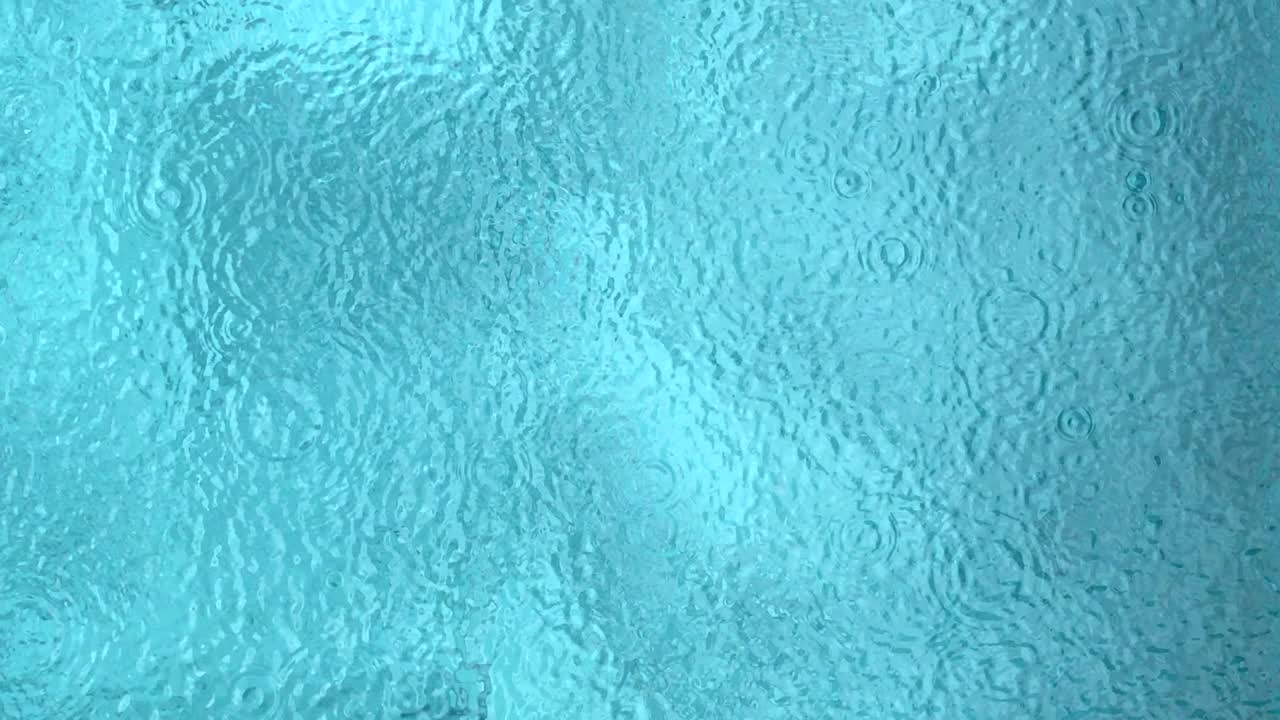 Vista superior de una gota de lluvia sobre la superficie del agua en una piscina.