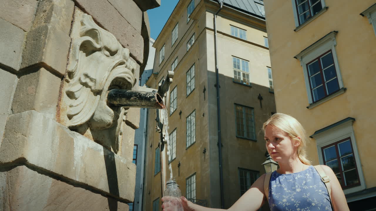 una mujer recoge agua en una botella de una fuente en la plaza central de estocolmo bebida limpia