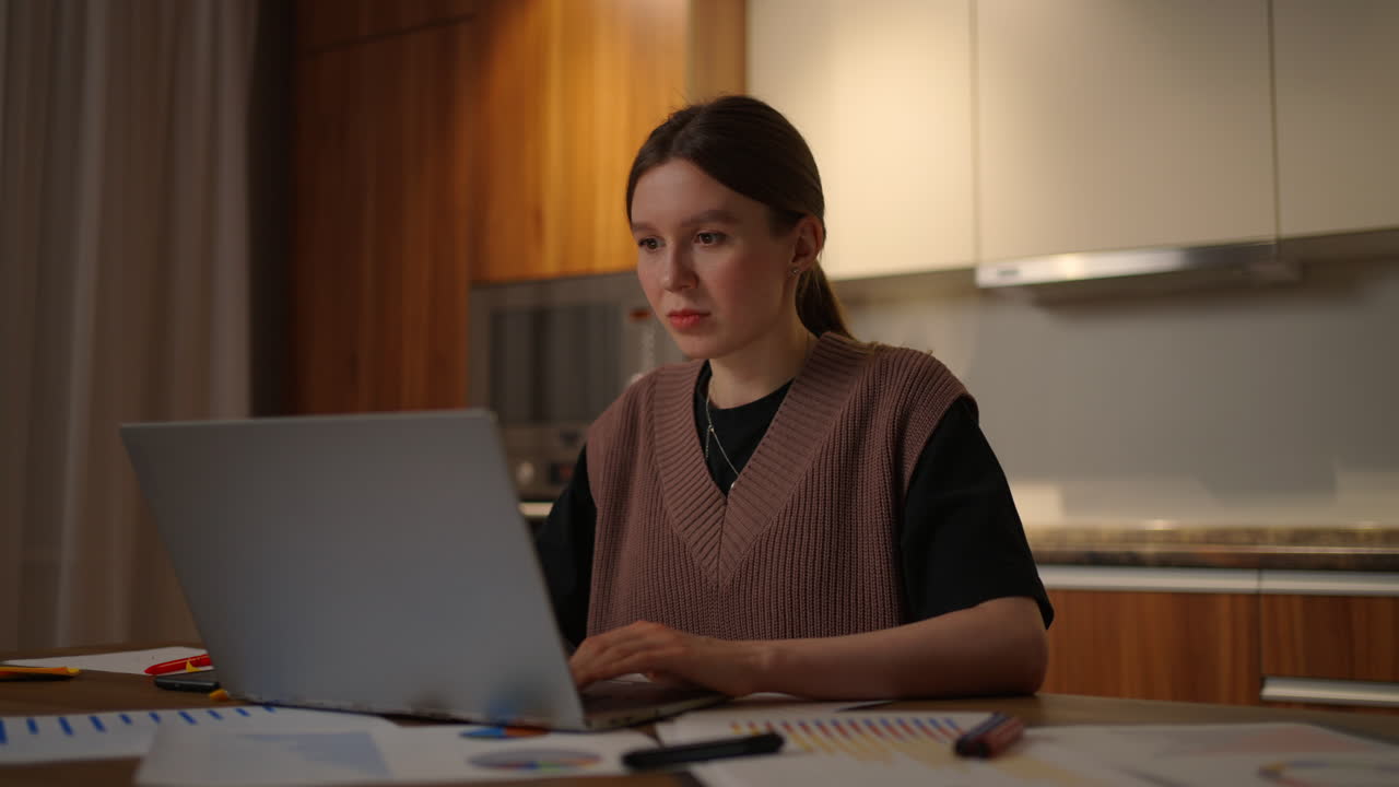 집에서 일하는 성숙한 사업가 여성은 집에서 부 ⁇ 에 앉아 노트북과 종이 문서를 가지고 일하고 있습니다. 노트북 앱은 비용을 계산하고 비용을 예산하고 프로젝트를 예산합니다.