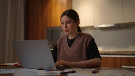 mujer de negocios madura que trabaja desde casa centrada mujer está trabajando con su computadora portátil y documentos en papel sentada en la cocina en casa. aplicación de computadora portátil calcular costos gastos presupuesto estimado para el proyecto