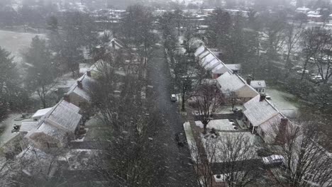 Aerial-descending-drone-shot-of-small-American-neighborhood-as-flurries-fly-on-winter-day