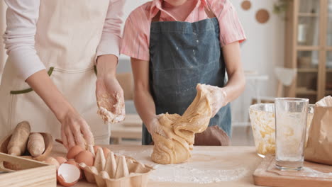 unrecognizable girl and her mother kneading dough