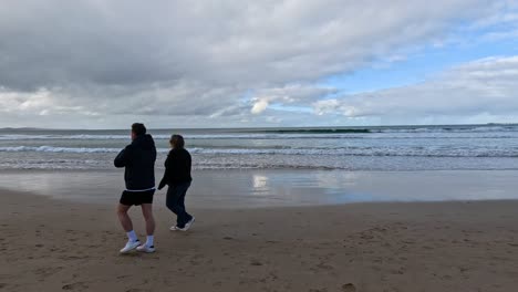 dos personas caminando a lo largo de una playa