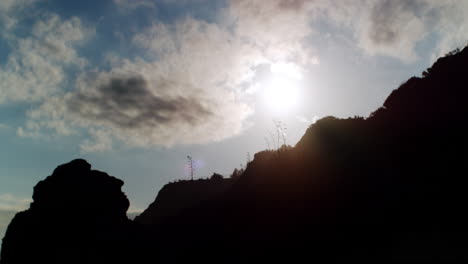 silhouetted hills against a bright sky with clouds