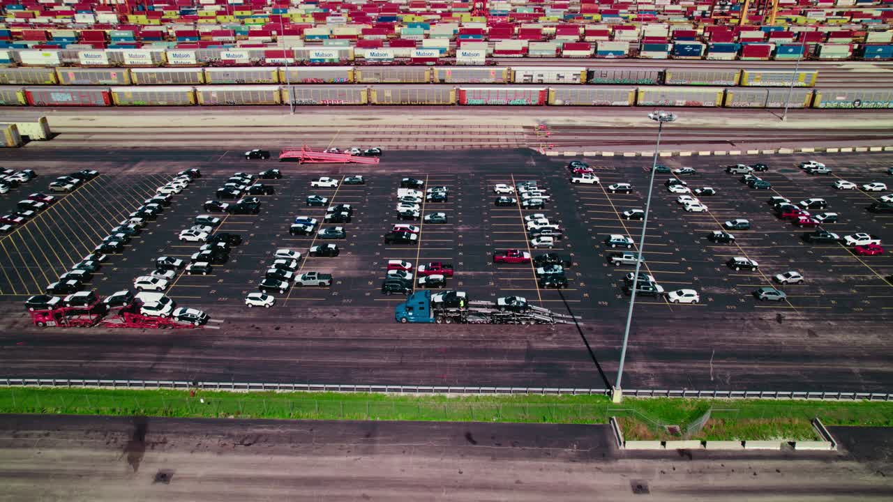 Aerial landscape view of a car carrier trailer, car hauler truck, loading cars from a parking lot